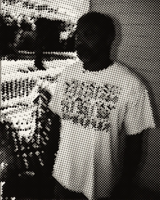 Geronimo Pratt stands on a porch in a patterned T-shirt, looking to the side.