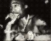 Tupac at the microphone, bare-chested, with chains and rings.